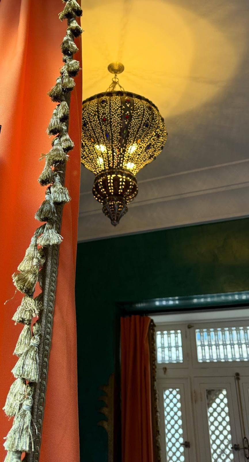 Moroccan lantern with silk tassels and orange curtains